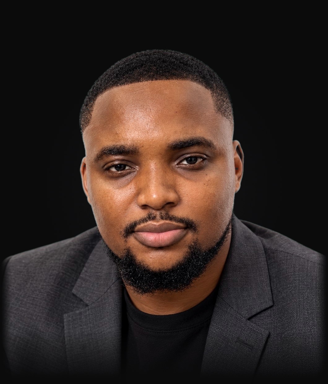 Studio portrait of Stephen Chinedu Anigbo, MBBS, in a charcoal blazer against a dark background